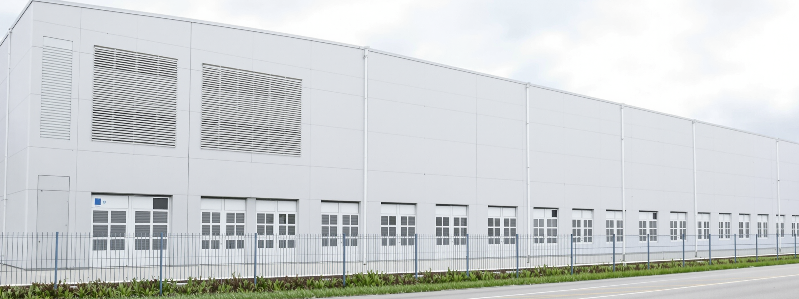 A long windowless data centre building behind a perimeter fence