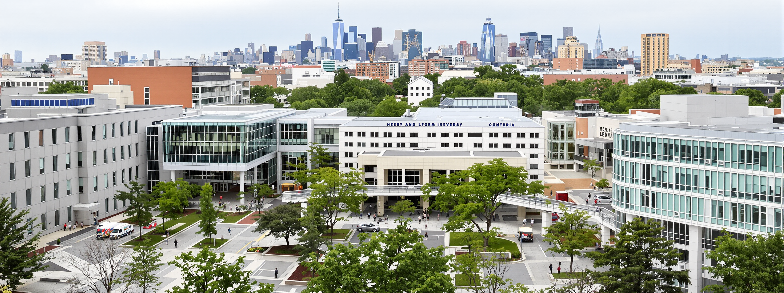 A dense urban university campus with a city skyline behind it
