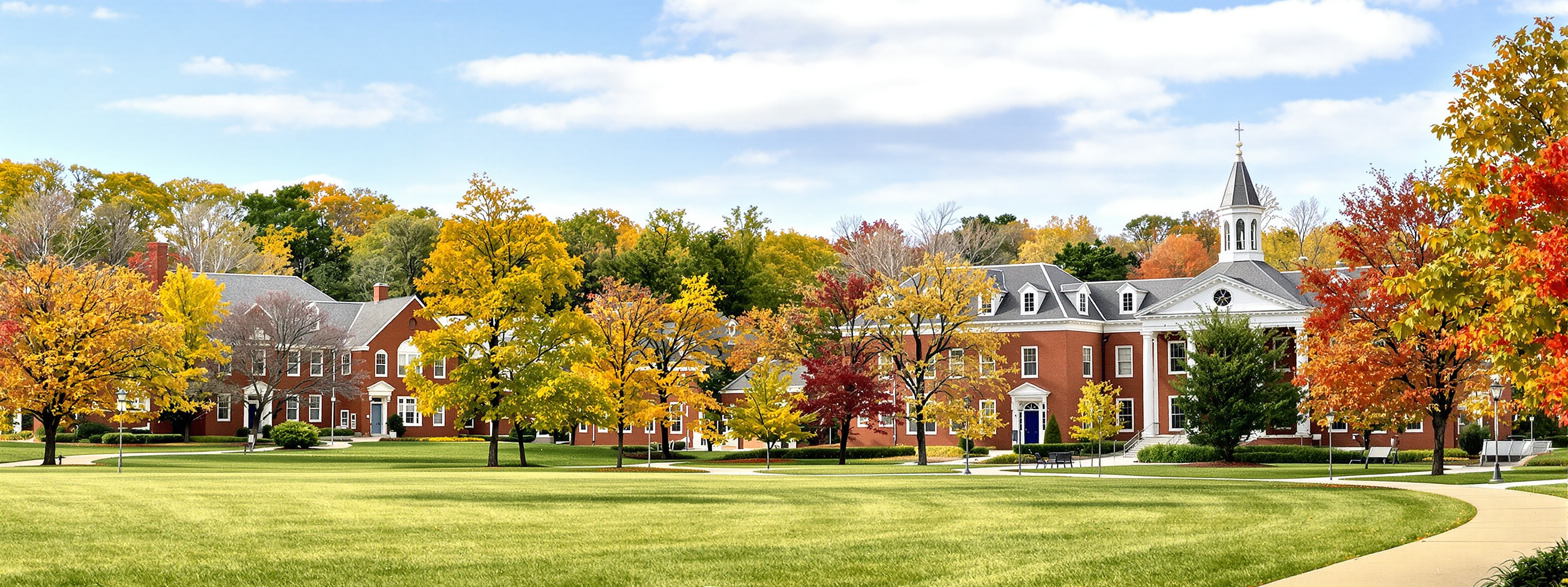 Red brick university buildings among autumn trees on an open lawn